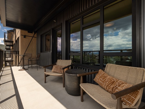 Settle into your private balcony where textured seating invites quiet mornings with coffee and golden afternoons watching clouds drift over the valley and distant hills.