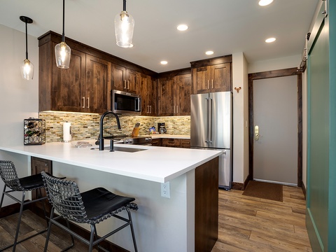 You'll love gathering around this spacious island, with its gleaming countertops, warm wood cabinetry, and modern appliances ready for your favorite meals. Cozy pendant lights set the perfect mood for morning coffee or evening conversations.
