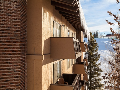 Mountain slope lodging with private balconies overlooking winter ski terrain and wooded areas. Each level opens to crisp alpine air and surrounding evergreen scenery.
