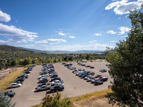 Elevated perspective showcasing ample parking amid a scenic mountain valley setting with forested slopes and open skies.