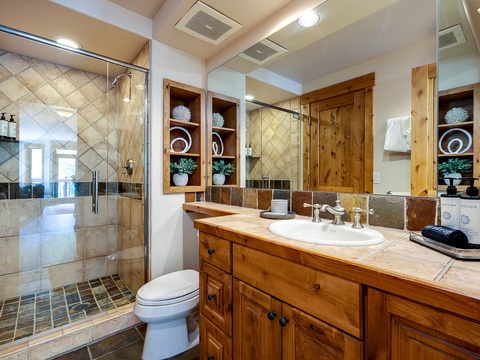 Step into a beautifully appointed bathroom where warm wood tones meet elegant tile work. Your morning routine becomes a ritual in this spa-like space, complete with a spacious walk-in shower and thoughtful touches that make you feel right at home.