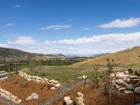 Scenic natural landscape surrounds the property, with rolling hills and distant mountain vistas creating a peaceful, open setting under expansive skies.