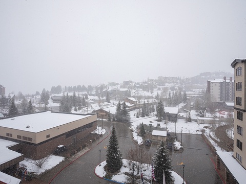 Snowfall blankets the surrounding mountain neighborhood, visible from the property during the serene winter season.