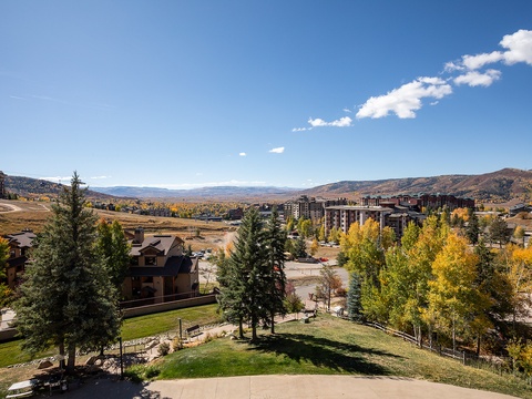 A mountain resort community nestled in the valley, framed by rolling hills and golden autumn aspens under a clear blue sky.