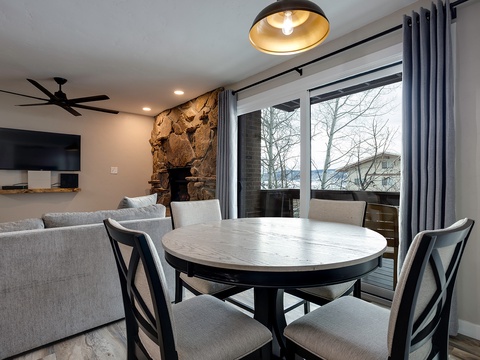 Gather around this inviting dining table with a cozy stone fireplace and comfortable seating, while natural light streams in from your private balcony overlooking the peaceful surroundings.