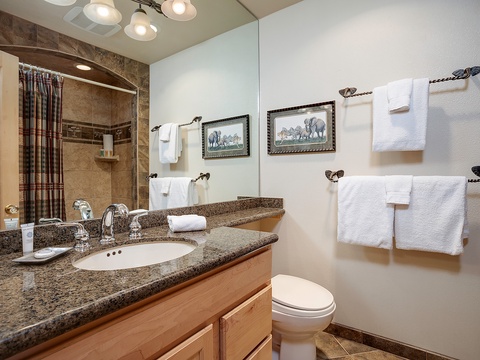 Step into your private bathroom, where rich granite countertops, warm wood cabinetry, and plush towels await. The tiled shower and thoughtful touches create a welcoming retreat after your day of adventure.