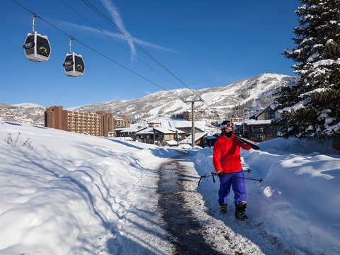 A winter ski resort nestled in snow-covered mountains, featuring gondola lifts, lodging buildings, and surrounding natural landscape. The area offers easy access to slopes and alpine scenery.