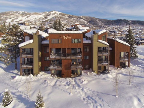 The West sits nestled in snow-covered mountains, a contemporary vacation property with multiple balconies overlooking the valley and ski slopes. Winter sports and alpine adventures await nearby.