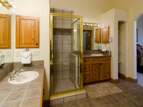 Your private en-suite bathroom features dual vanities, a walk-in shower with glass enclosure, and warm wood cabinetry—perfect for refreshing after a day of adventure.