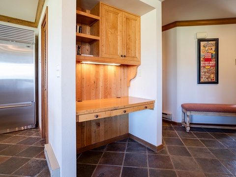 Your entryway features custom wood cabinetry with warm under-lighting, tile flooring, and a cozy bench for easy arrivals and departures—a welcoming space to settle in.