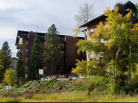 This distinctive alpine-style property sits nestled among vibrant golden aspens and evergreen pines. The multi-level building features a natural mountainside setting with seasonal autumn foliage framing the entrance.