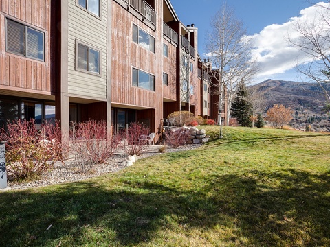 Mountain property with multi-level exterior, manicured lawn, and sweeping views of the surrounding peaks and natural landscape.