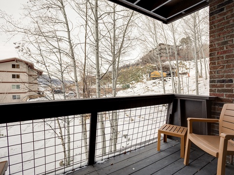 This property is nestled in a mountain setting surrounded by bare aspens and snow-covered slopes, offering a peaceful winter retreat with nearby buildings visible in the landscape.