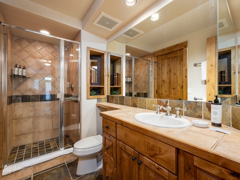 Step into your elegant bathroom, complete with a tiled walk-in shower, custom wood cabinetry, and soothing lighting that makes every morning feel special.