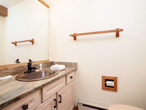 Your private bathroom features a hammered copper sink set in a beautiful granite counter, with rustic wooden accents and plush white towels ready for your comfort.