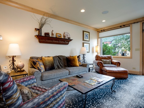 Settle into this inviting living room where natural light pours through large windows, framing peaceful neighborhood views. Sink into plush seating surrounded by warm wood accents and thoughtful decor that makes every moment feel like home.