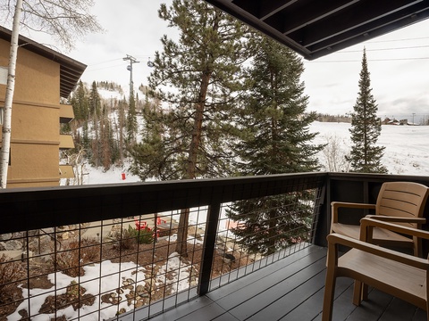 The balcony overlooks snowy ski slopes and evergreen trees, framing a serene mountain-view perfect for après-ski relaxation after a day on the trails.
