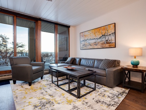 Unwind in your cozy living room with a stunning lake view framed by floor-to-ceiling windows. Sink into the plush leather sofa and let the natural light and peaceful scenery wrap you in comfort.
