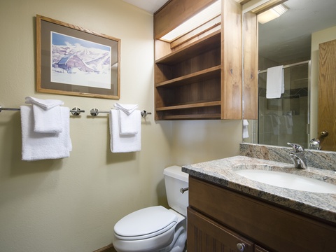 Your private bathroom features a granite vanity, plush towels, wooden cabinetry, and convenient storage shelves—everything you need to feel refreshed and at home during your mountain getaway.