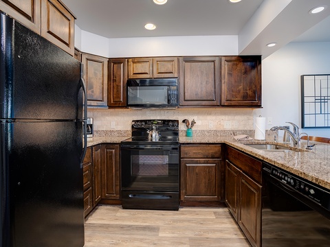Your fully equipped kitchen features rich wood cabinetry, granite countertops, modern appliances, and everything you need to prepare delicious home-cooked meals during your stay.