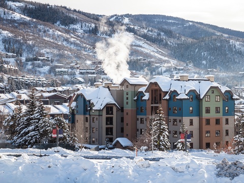Winter alpine village nestled at the base of snow-covered mountain slopes, surrounded by evergreen forests and scenic peaks—an idyllic location for a mountain getaway.