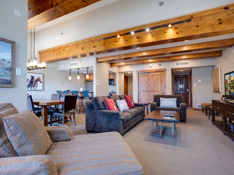 Unwind in your spacious open-concept living area, featuring soaring vaulted ceilings with rustic beams, plush seating, and mountain-inspired artwork that sets the tone for your alpine escape.