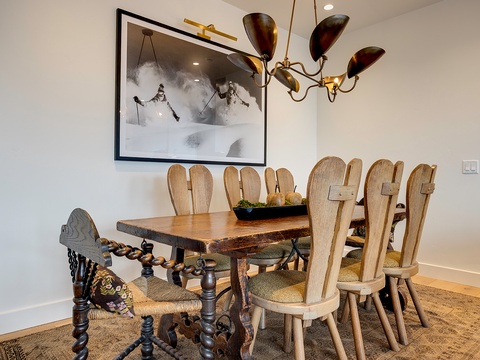 Gather around this unique dining table, where distinctive alpine-inspired chairs and vintage chandelier lighting create a cozy setting for your mountain retreat meals and evening conversations.