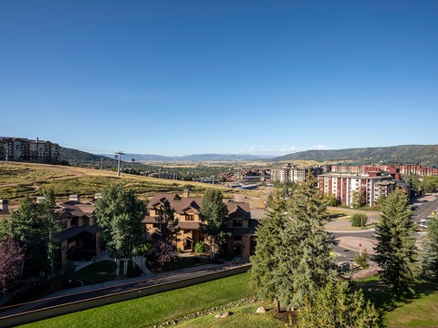Expansive mountain views frame this resort community, surrounded by rolling hills and open valleys under clear blue skies.