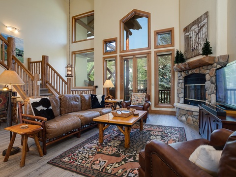 Picture yourself unwinding in this inviting mountain retreat, where soaring windows flood the space with natural light, and a crackling stone fireplace creates the perfect après-ski ambiance.