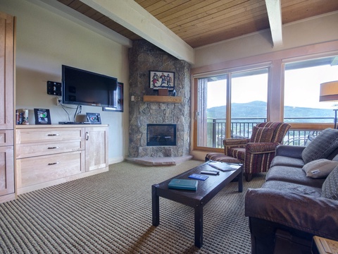 Unwind in your cozy living space where mountain views stretch beyond floor-to-ceiling windows. Curl up by the stone fireplace and let the peaks inspire your next adventure.