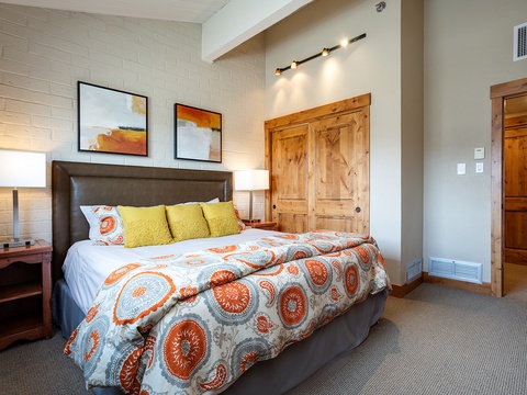 Sink into this cozy bedroom with its plush bed, warm lighting, and artistic touches. Your peaceful retreat awaits with natural wood accents and soft textures.