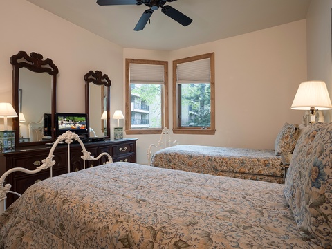 Your comfortable bedroom features elegant furnishings, two plush beds with ornate bedding, charming vintage mirrors, and soft lighting to help you unwind after exploring.