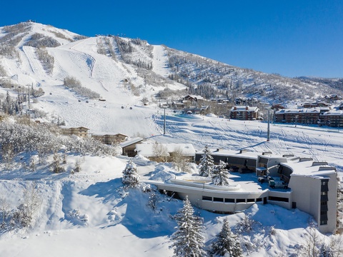 This mountain retreat sits at the base of pristine ski slopes, surrounded by snow-covered peaks and evergreens—a winter wonderland setting in the heart of resort country.