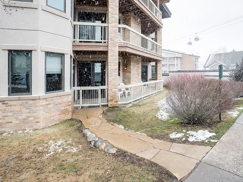A multi-level brick building exterior with private balconies, set in a quiet residential neighborhood during late winter or early spring.