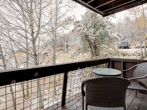 A snow-dusted balcony overlooking peaceful wooded surroundings, with cozy seating awaiting your morning coffee or evening unwind amid a serene winter landscape.