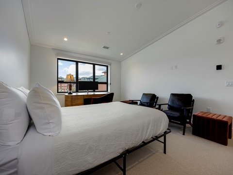 Sink into crisp white linens after a day exploring the city. Two cozy chairs invite you to relax by the window, while a modern wood desk offers a perfect workspace with urban views.