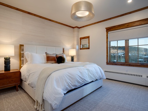 Sink into plush bedding and wake to stunning mountain views framed by warm wood accents. Your restful retreat awaits with soft lighting and serene style.