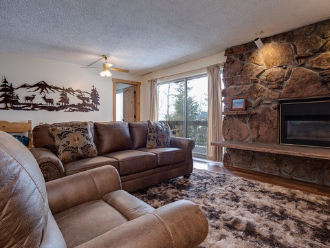 Settle into plush leather sofas beside a stunning stone fireplace, where rustic mountain charm meets modern comfort. Large windows frame scenic views while you relax in this cozy, inviting living room.