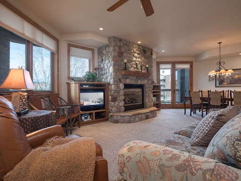 Gather around the river rock fireplace in this inviting living space where plush seating, warm wood accents, and mountain views create your perfect retreat after a day of adventure.