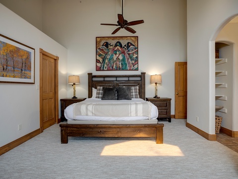 Step into your spacious primary suite, where vaulted ceilings, rich wood accents, and sunlight streaming across soft carpets invite you to unwind in peaceful comfort.