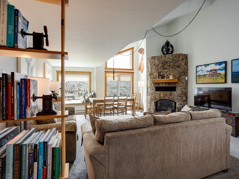 Curl up with your favorite book in this bright living room, where soaring ceilings, a cozy stone fireplace, and mountain views create the perfect retreat.