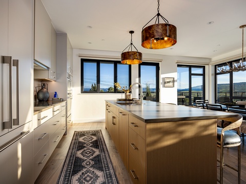Gather in a sleek, sunlit kitchen where rustic pendant lights and sweeping mountain views set the scene for memorable mornings and shared meals with loved ones.