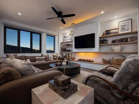 Sink into plush sectional sofas by the glowing fireplace, where mountain views frame your evenings and warm textures create your perfect retreat.