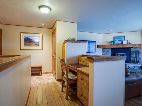 Your vacation home features a cozy living space with warm wood furnishings, a charming stone fireplace, and a dedicated workspace perfect for catching up on emails or planning your next adventure.