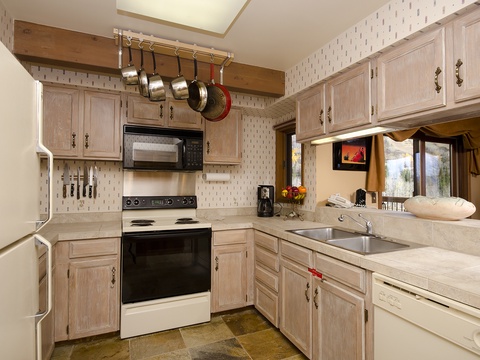You'll love preparing meals in this fully equipped kitchen, where pots and pans hang within easy reach, bright counters offer plenty of space, and natural light pours in through the window.