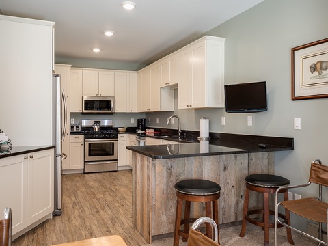 Your fully equipped kitchen awaits with stainless steel appliances, granite countertops, and a breakfast bar perfect for morning coffee or casual dining while watching your favorite shows.