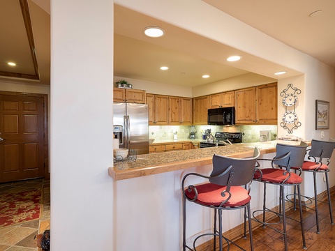 Your spacious kitchen features warm wood cabinetry, granite countertops, and a breakfast bar with seating for four—perfect for morning coffee or casual meals together.