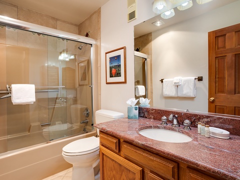 Step into your private bathroom, where warm wood cabinetry and polished granite countertops create a welcoming space. Fresh towels await, and the walk-in shower promises a refreshing start to your mountain mornings.