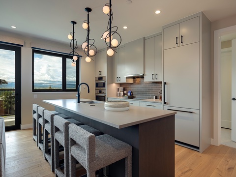 Modern kitchen with coastal views through expansive windows—perfect for preparing meals while enjoying the serene waterfront scenery beyond.