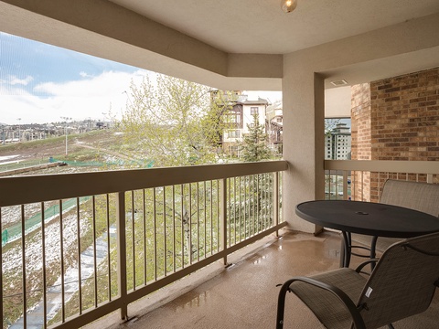 A covered balcony overlooking a peaceful neighborhood and nearby creek. The outdoor table and chairs provide the perfect setting to enjoy morning coffee or plan your day's adventures.